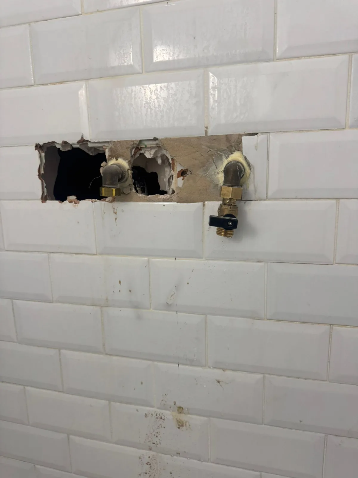 Ouverture ciblée dans la faïence d'une salle de bain pour accéder à la fuite localisée